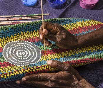 image of womans hand painting a colourful dot painting